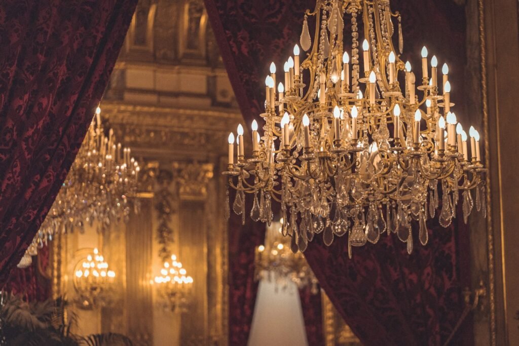 Crystal chandelier switched on, glowing warm against a dark ceiling