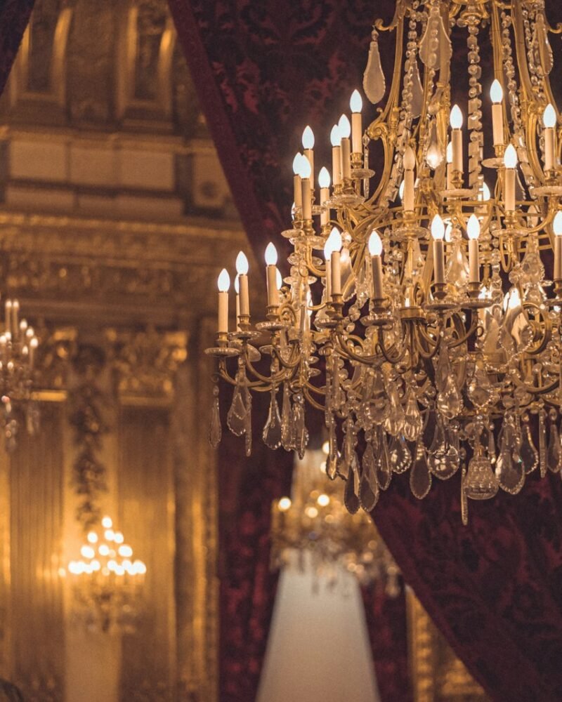 Crystal chandelier switched on, glowing warm against a dark ceiling